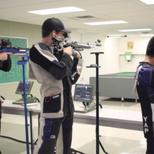 Rifle athletes prepare to shoot targets in competition.